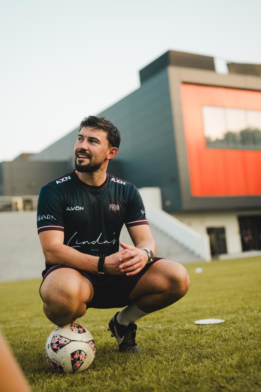 Jason Murphy crouching with a football on the pitch